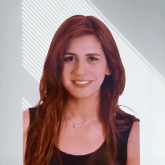 A woman with long brown hair and a necklace, smiling against a light background with diagonal lines.