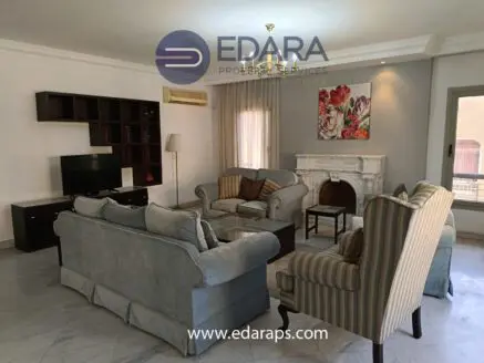 Living room with a light blue sofa set, a television, and a decorative fireplace in a neutral-toned space.