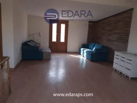 Living room interior with two blue sofas and wooden flooring in a spacious layout.