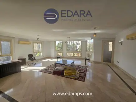 Spacious living area with marble flooring, large windows, and a central table in a residential property.