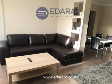 Living room scene with a dark brown leather sectional sofa and a light wooden coffee table, Edara Property Services logo overlay, dining area in background