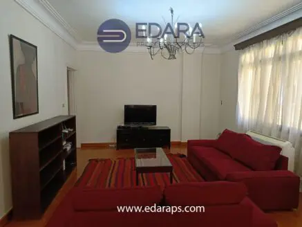 Living room with red sofas, a coffee table, and a television on a black cabinet.