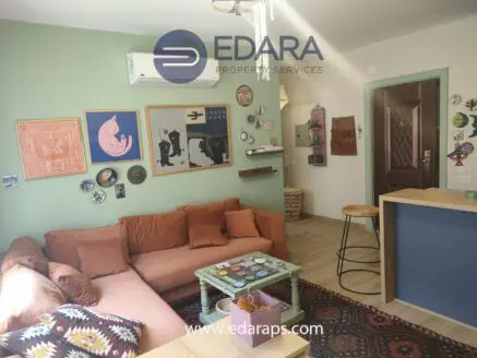 Living room with a brown sofa, decorative wall art, and a wooden bar counter in a modern interior.