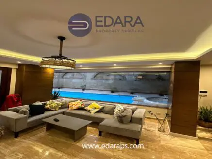 Modern living room with a sectional sofa, decorative cushions, and a view of a swimming pool.