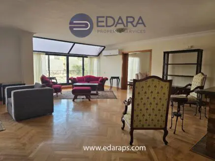 Spacious living room with modern furniture, featuring a large window and stylish seating arrangements.
