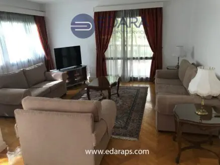 Living room with beige sofas, a wooden coffee table, and a television in a well-lit space.
