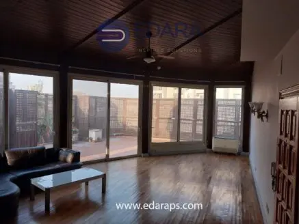 Spacious living room with wooden ceiling, large windows, and a modern sofa set in a residential space.