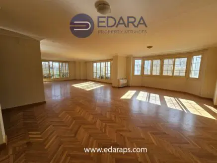 Spacious interior of a property with wooden flooring and large windows allowing natural light.