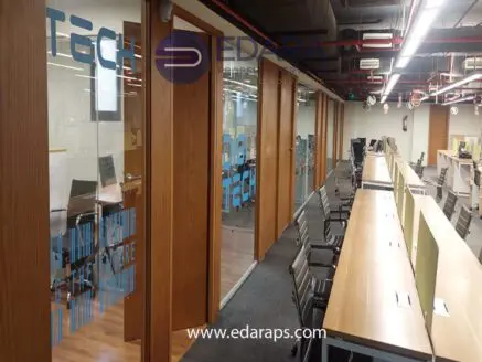 Interior view of an office space with wooden doors and modern desks arranged in a row.