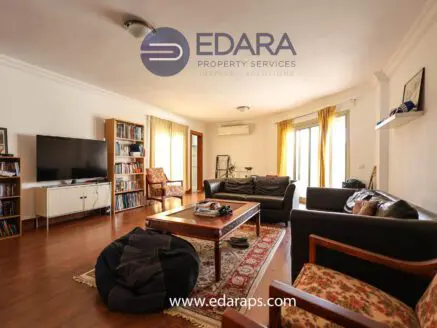 Living room interior with a television, bookshelves, and comfortable seating arrangements.
