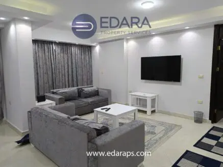 Living room with gray sofas, a white coffee table, and a wall-mounted television in a modern interior setting.