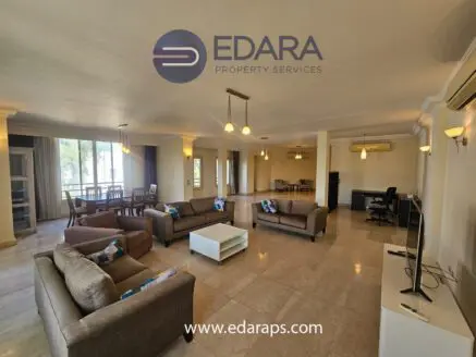 Spacious living room with modern furniture, including sofas, a coffee table, and a dining area in a well-lit interior.