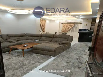 Living room with a large brown sectional sofa, wooden coffee table, and modern lighting fixtures.
