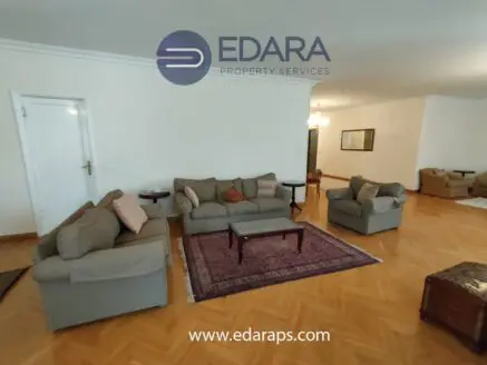Living room with a gray sofa set, armchairs, and a coffee table on a patterned rug in a spacious area.
