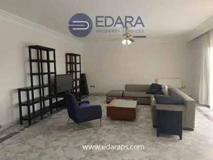Living room with a sectional sofa, coffee table, and shelves in a spacious layout.