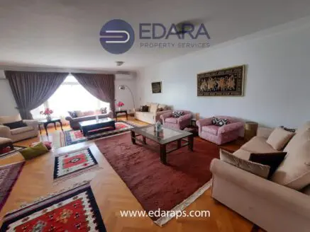 Spacious living room with beige sofas, a coffee table, and decorative rugs in a residential setting.