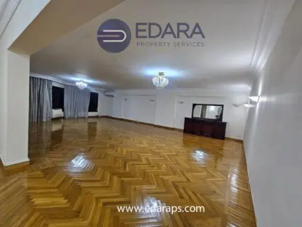 Spacious interior of a room with polished wooden flooring and elegant lighting fixtures.