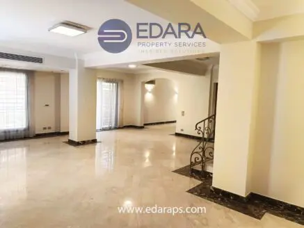 Spacious interior of a residential property with marble flooring and natural light from large windows.