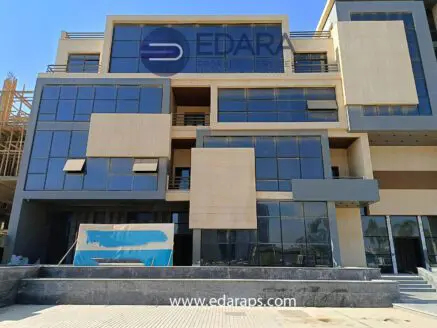 Modern building exterior with large glass windows and beige stone facade in Cairo.