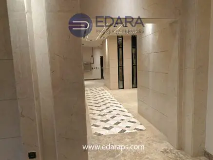 Interior hallway with marble walls and patterned flooring in a modern building.