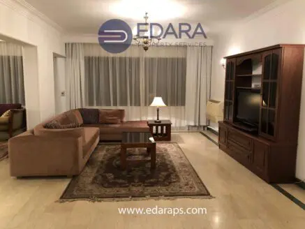 Living room with a brown sectional sofa, wooden coffee table, and television unit in a well-lit space.
