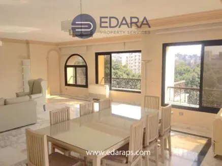 Spacious living area with large windows, dining table, and modern furniture in a residential setting.