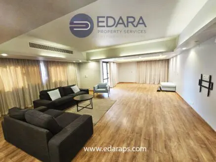 Modern living room featuring a gray sofa set, coffee table, and large windows with curtains.