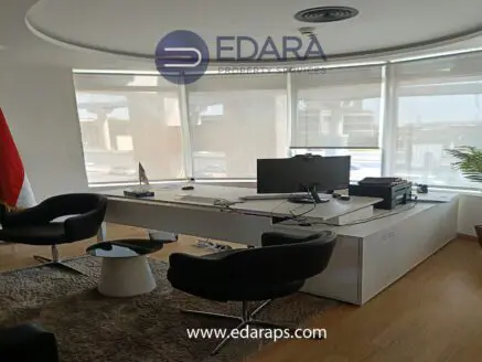 Modern office workspace featuring a desk, computer, and black chairs in a well-lit environment.