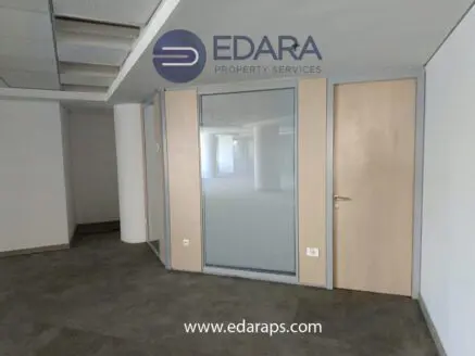 Interior view of an office space featuring a glass partition and wooden doors in a modern design.