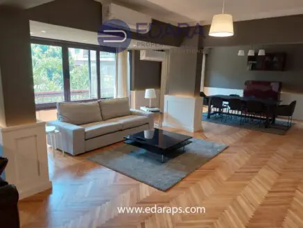 Living room with a gray sofa, coffee table, and dining area featuring a modern design and wooden flooring.