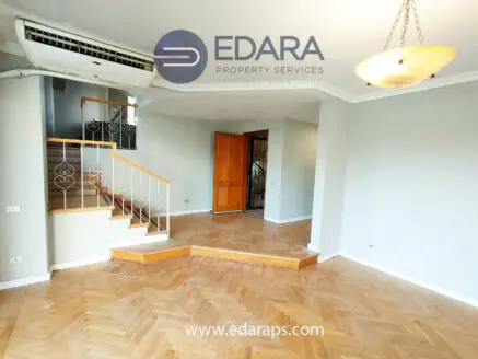 Interior of a residential space featuring wooden flooring and a staircase.