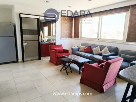 Living room featuring a gray sofa and red armchairs with a coffee table in a well-lit space.