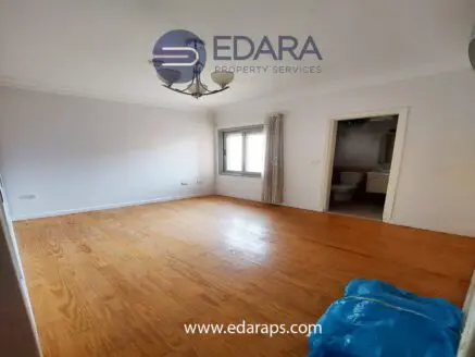 An empty room featuring wooden flooring and a window with natural light.