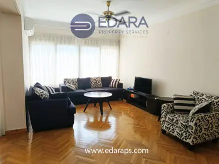 Living room featuring a dark sofa with striped cushions and a round coffee table in front of a television.