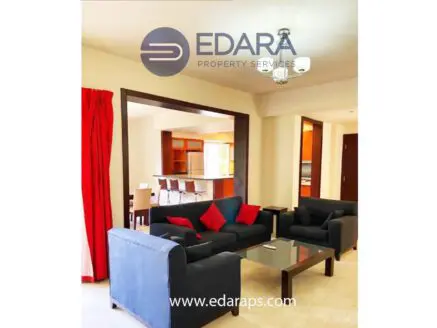 Living room featuring a dark blue sofa set with red cushions and a glass coffee table.