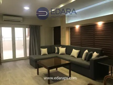 Modern living room featuring a gray sectional sofa with decorative pillows and a large window.