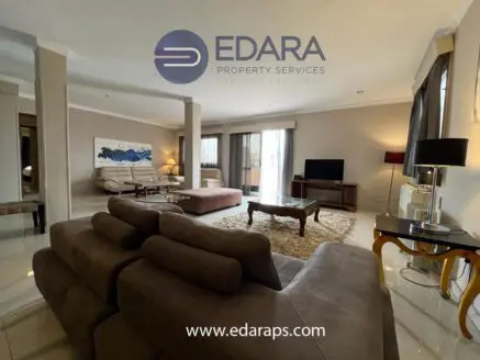 Living room interior featuring a brown sectional sofa, coffee table, and television in a well-lit space.