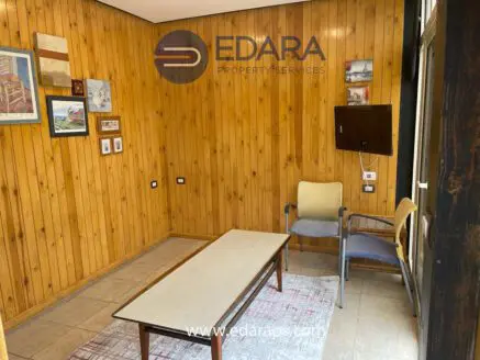 Interior view of a room with wooden paneling, a table, and two chairs in a simple layout.