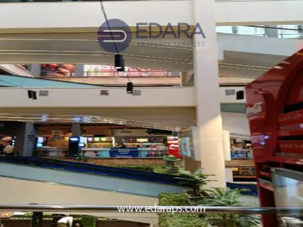 Interior of a shopping mall featuring escalators, shops, and food outlets across multiple levels.