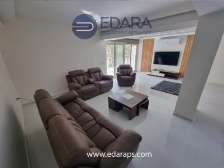 Living room with brown leather sofas, a coffee table, and a television mounted on the wall in a modern interior.