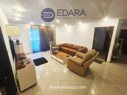 Spacious living room featuring a beige sofa set, coffee table, and large windows with curtains.