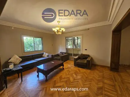 Living room with a brown sofa set, wooden coffee table, and large windows allowing natural light.