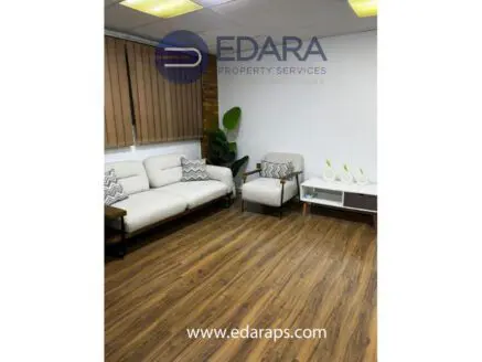 Modern office seating area with a light-colored sofa, armchair, and wooden flooring at Edara Property Services.