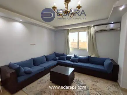Living room featuring a blue sectional sofa with cushions and a coffee table in a well-lit space.