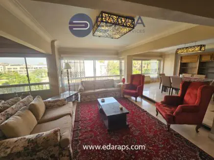 Spacious living room featuring red accent chairs, a floral sofa, and a decorative rug.