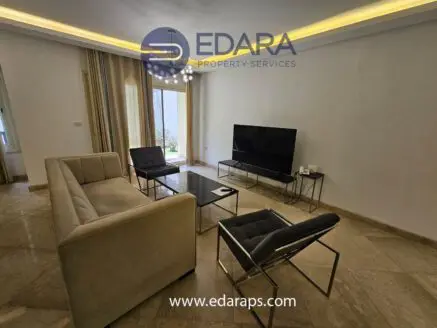 Contemporary living room featuring a beige sofa, two black chairs, and a television on a stand.