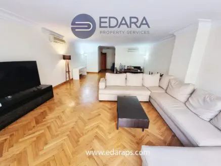 Spacious living room featuring a light-colored sectional sofa and a flat-screen television on a dark media console.