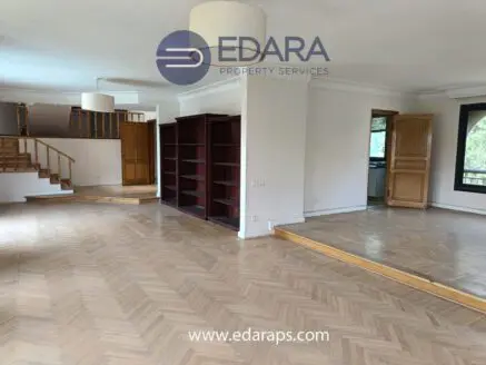 Interior view of a spacious living room featuring wooden shelves and a staircase.