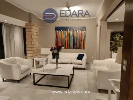 Living room featuring white sofas, a marble coffee table, and a colorful artwork on the wall.