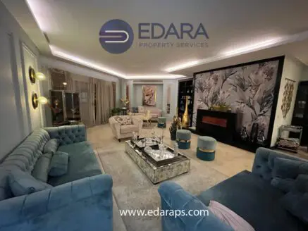 Contemporary living room featuring a blue sofa set, glass coffee table, and decorative elements.
